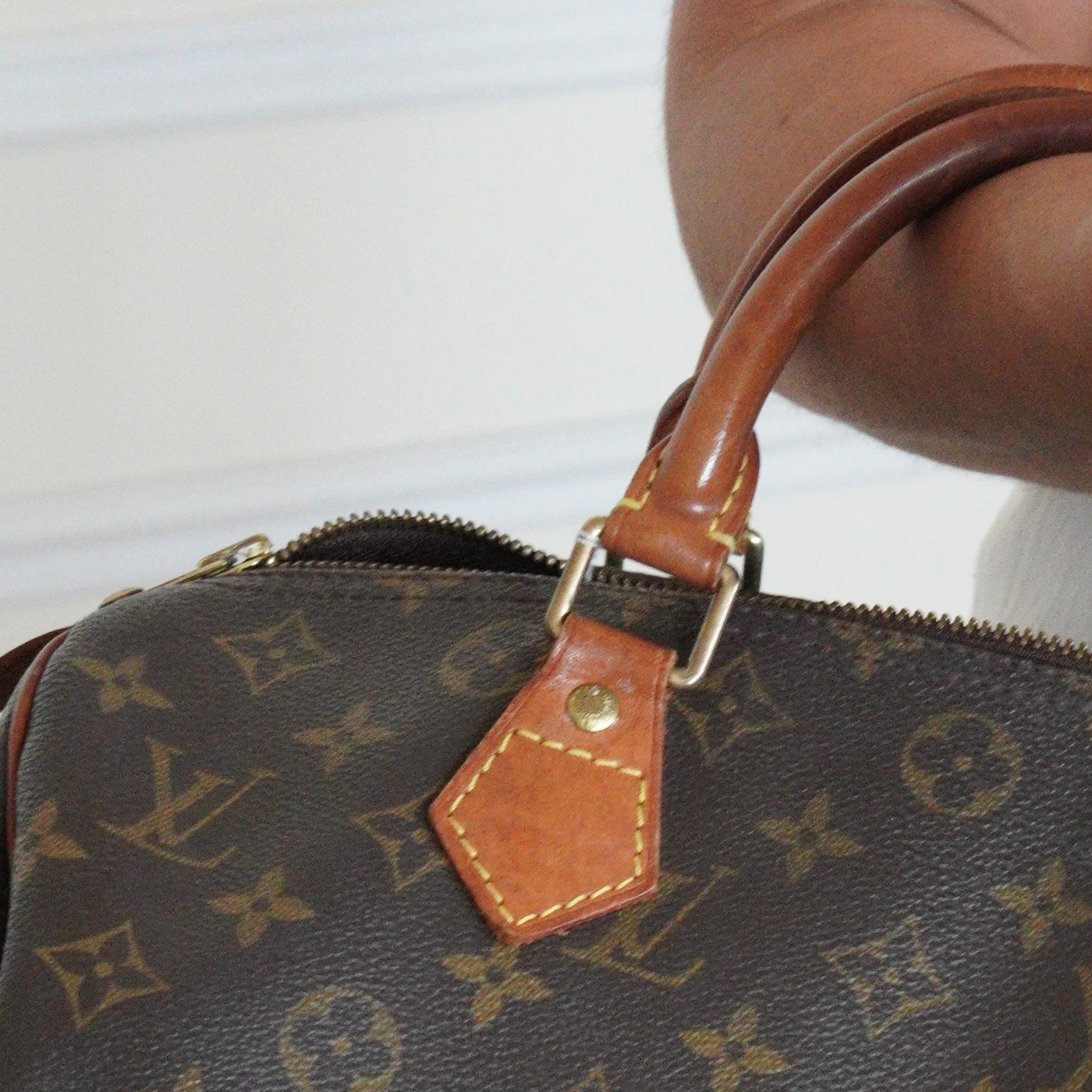 Vintage Louis Vuitton Speedy Monogram handbag showing natural leather patina on the handles.