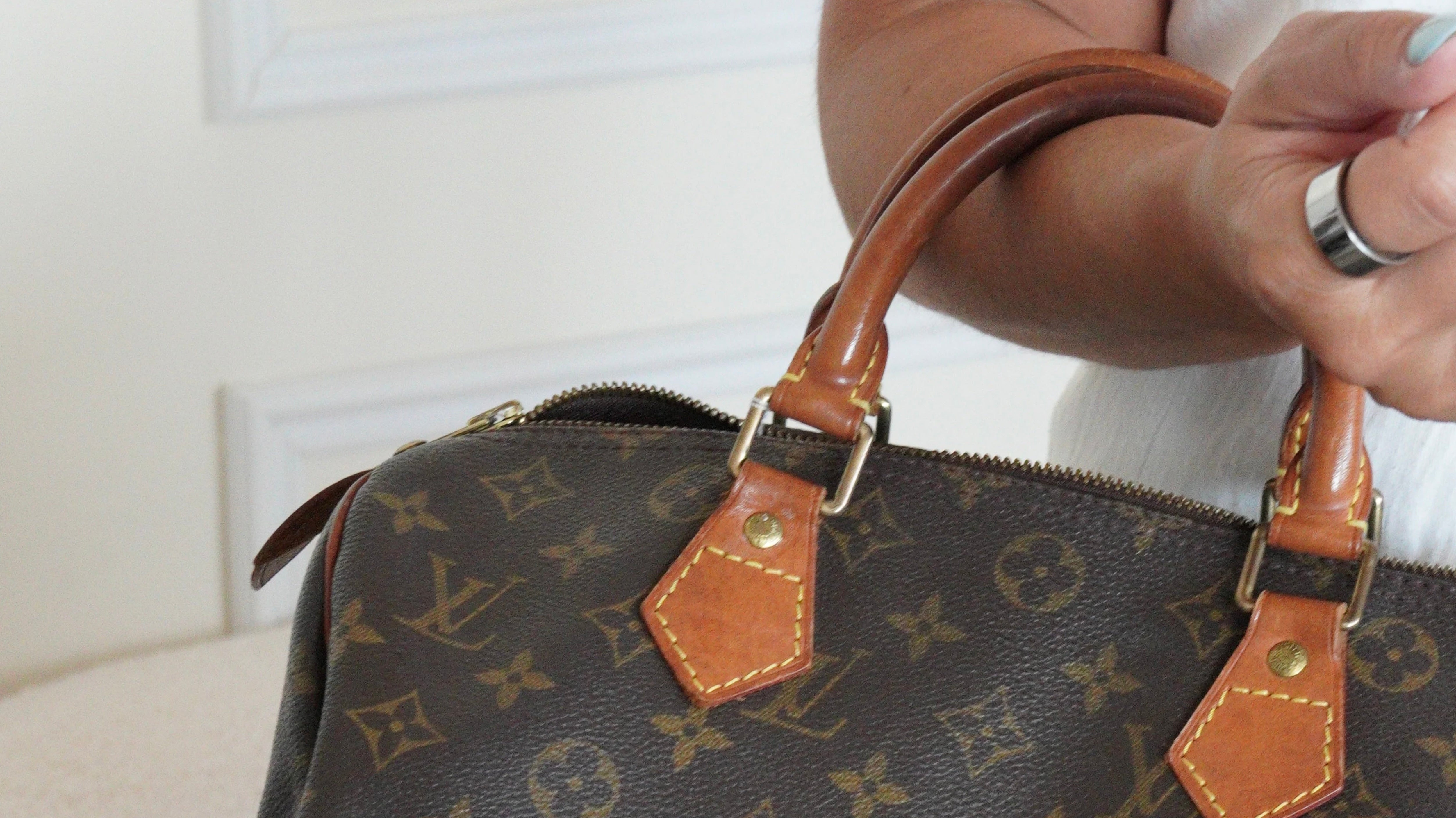 Vintage Louis Vuitton Speedy Monogram handbag showing natural leather patina on the handles.
