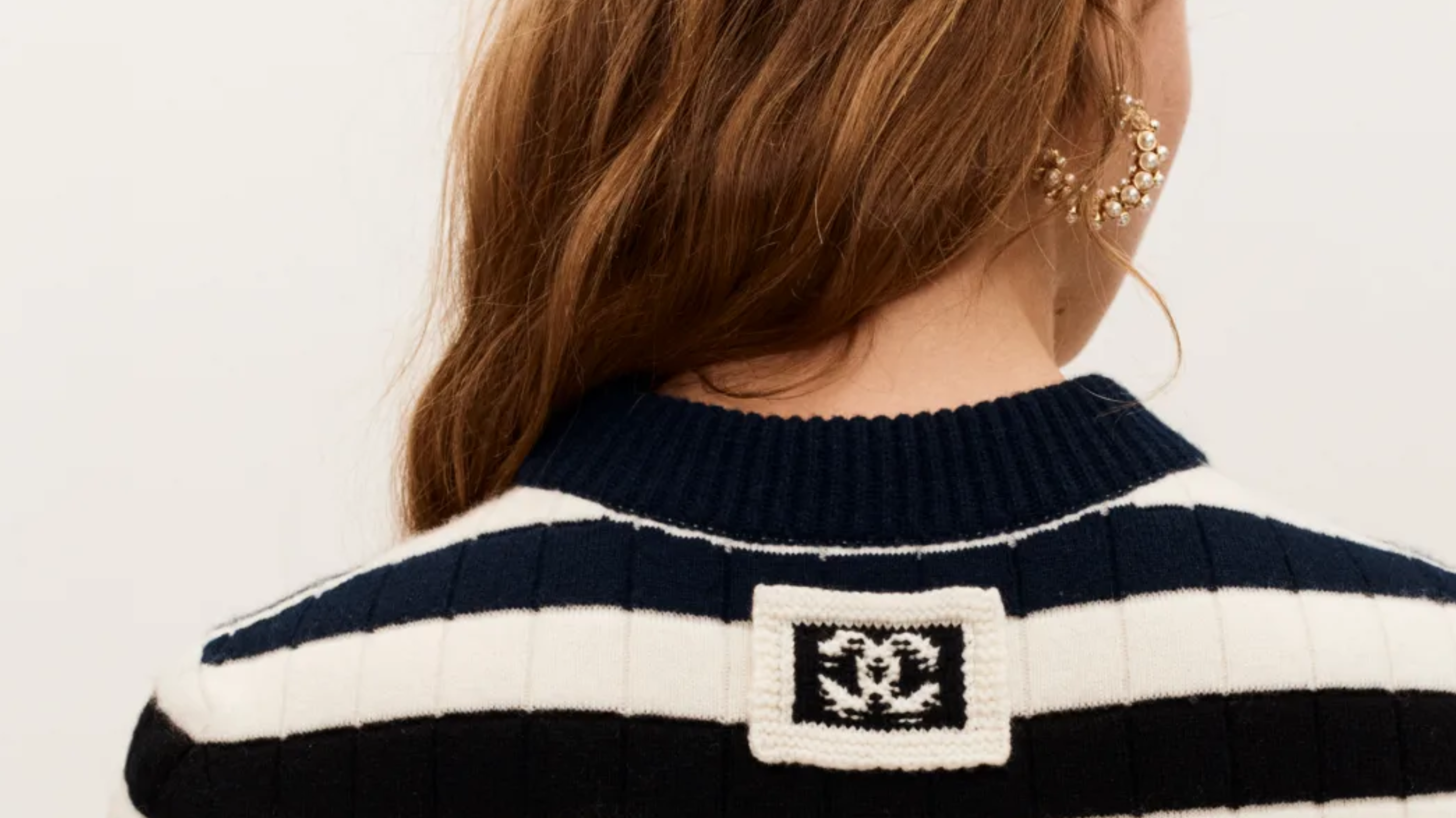 photo qui vient du site chanel, dos d'une femme qui a un pull rayé blanc et noir avec le logo chanel en assez gros