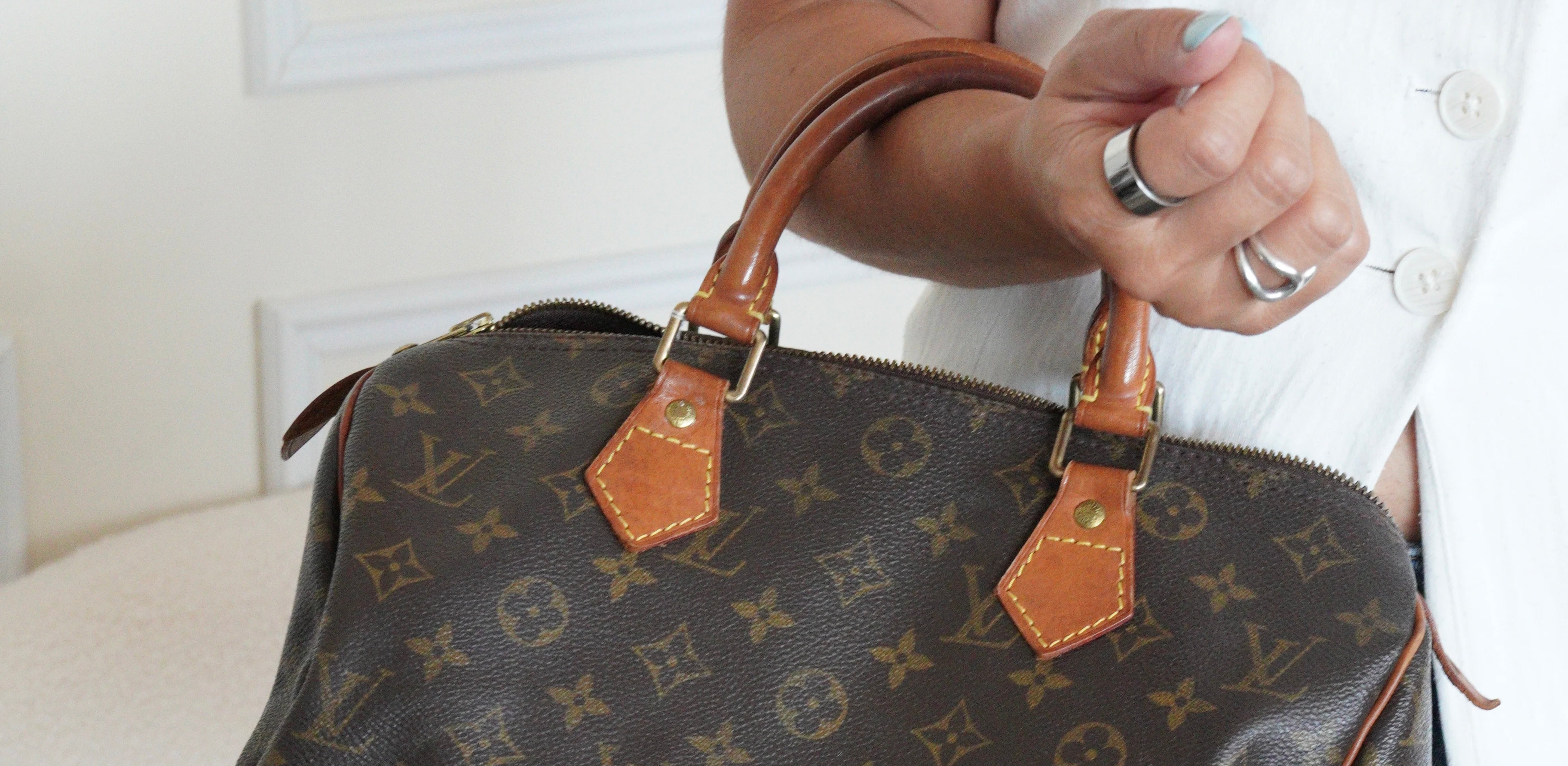 Vintage Louis Vuitton Speedy Monogram handbag showing natural leather patina on the handles.