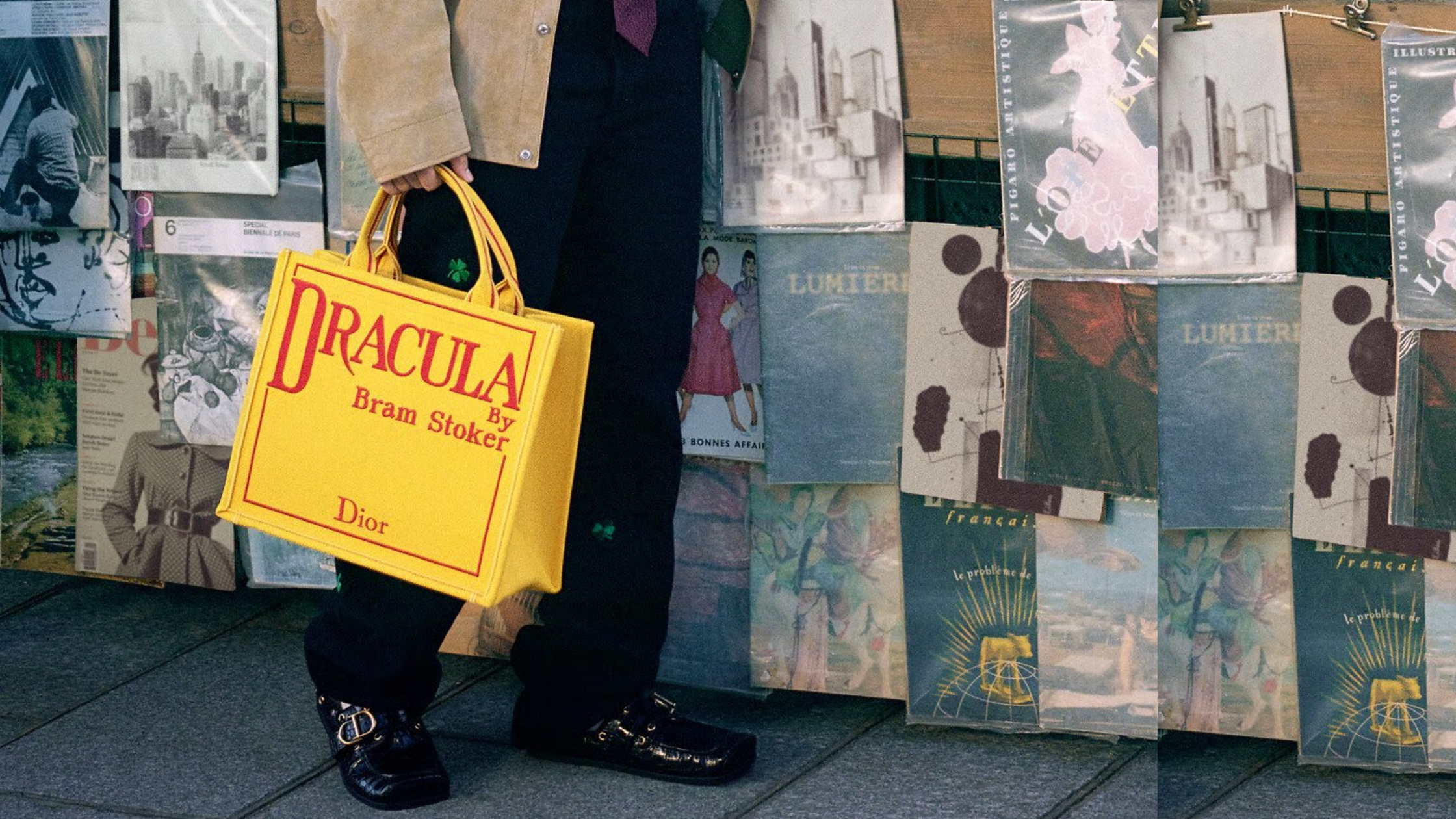 image d'un sac porté à la main d'un Dior Book Tote rouge et jaune  DRACULA avec des affiches en fond 